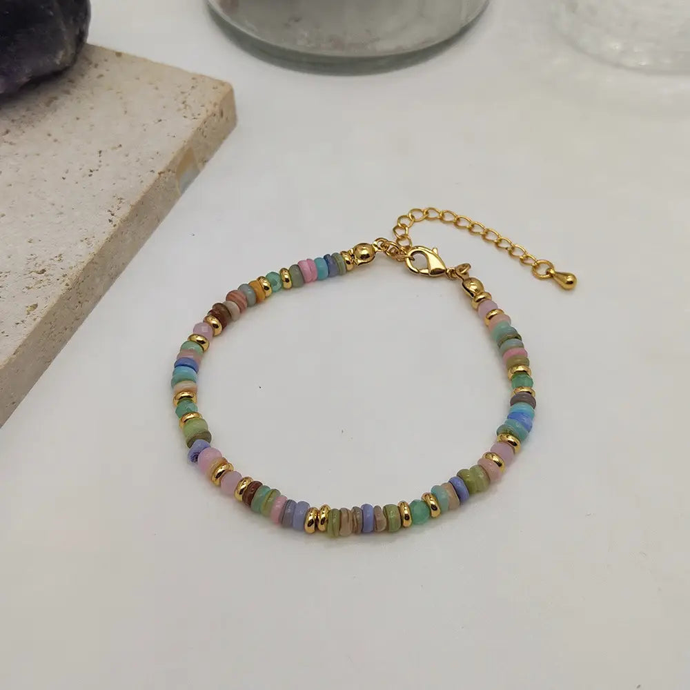 Handwoven rainbow shell beaded bracelet featuring pastel-colored beads with gold-toned metal accents and a gold clasp.