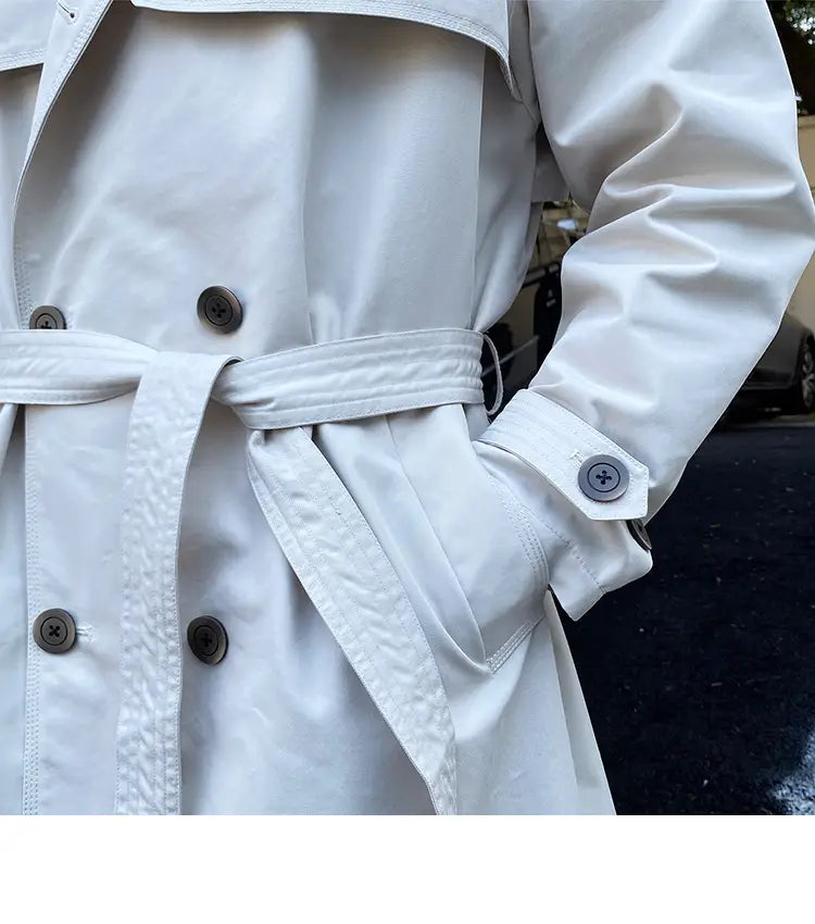 A crisp white double breasted trench coat for men with a belted waist and dark gray buttons.
