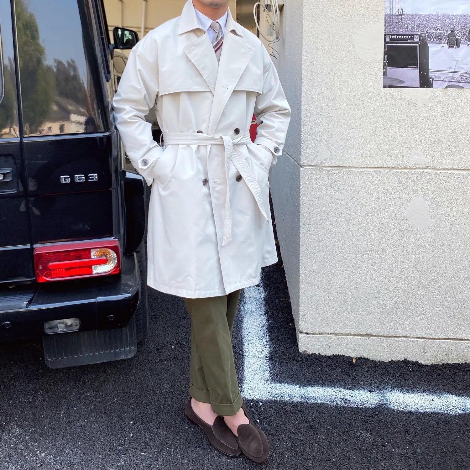 A crisp white double breasted trench coat for men featuring a belted waist and classic front closure.
