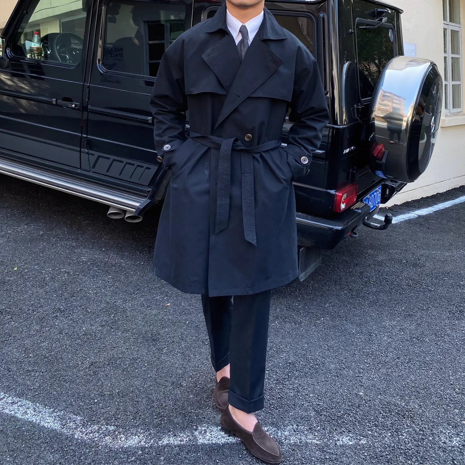 black double breasted trench coat for men featuring a belted waist and tailored fit.