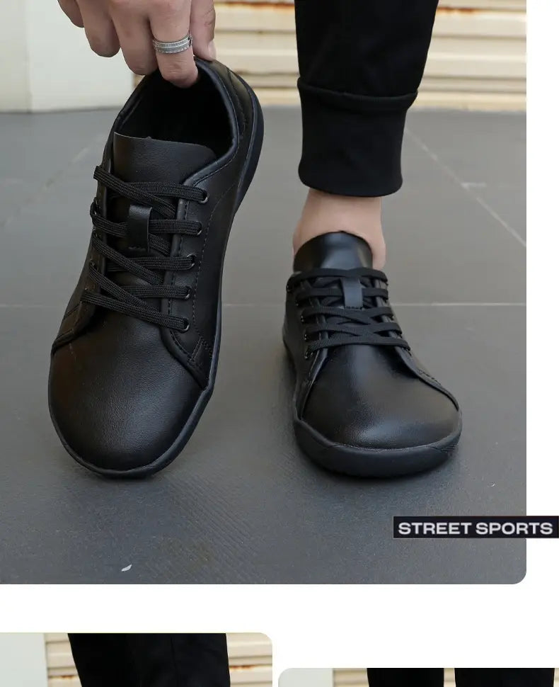 Zapatilla minimalista antideslizante de cuero negro de caña baja y puntera ancha con cordones negros y suela de goma plana.