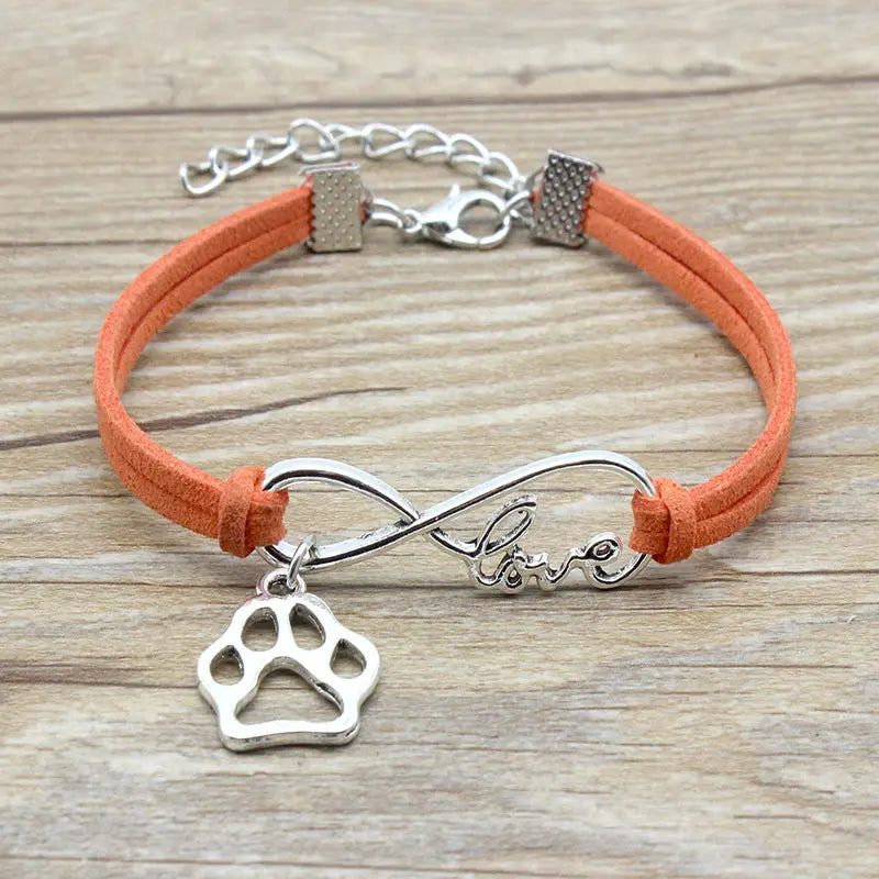 Orange suede cord hand-woven infinite love pet paw bracelet featuring a silver-toned infinity charm engraved with love and a dangling paw print pendant.