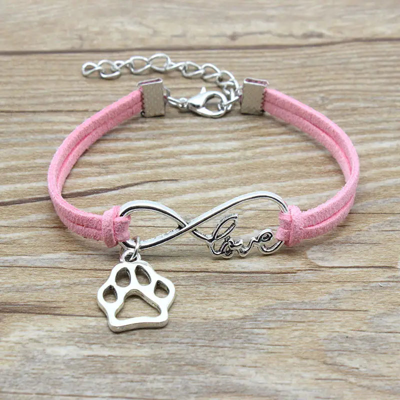 pink suede cord hand-woven bracelet featuring a silver infinity charm engraved with love and a dangling paw print pendant symbolizing infinite love for pets.