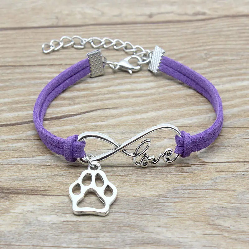Purple suede hand-woven infinite love pet paw bracelet featuring a silver infinity charm engraved with love and a dangling paw print pendant.