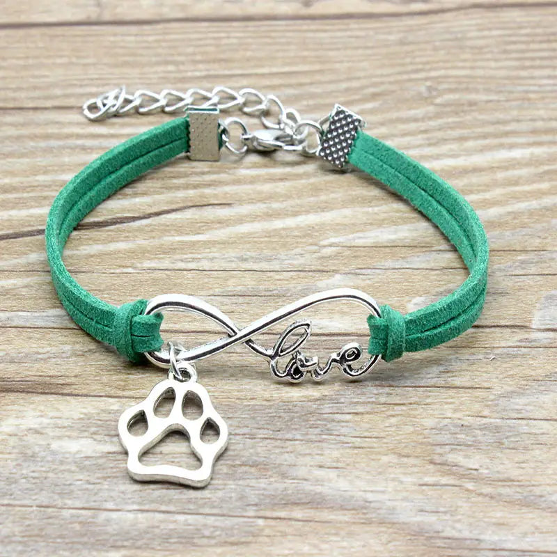 green suede hand-woven bracelet featuring a silver infinity charm engraved with love and a paw print pendant designed for pet lovers.