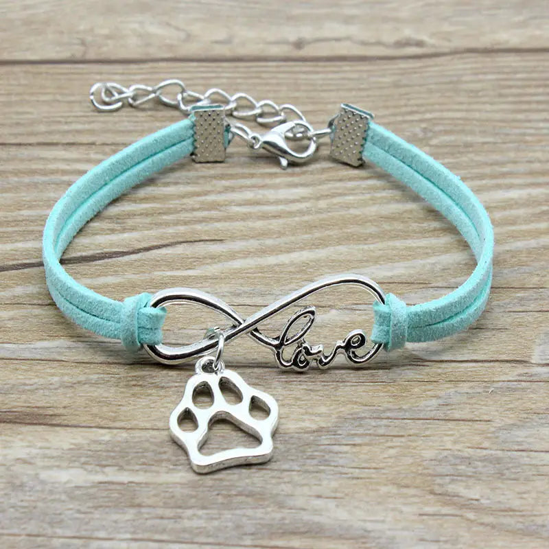 A hand-woven mint green suede bracelet featuring a silver infinity symbol charm with the word love and a paw print pendant.