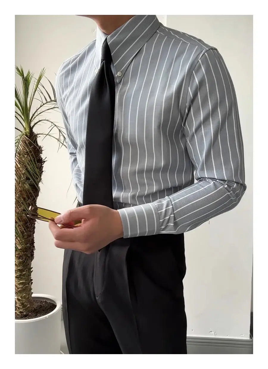 Herren-Slim-Fit-Hemd mit vertikalen Streifen, langem Ärmel, für den Business-Einsatz, aus kühlem grauem und weißem Baumwollgewebe mit klassischem Kragen, getragen zu schwarzen Hosen.