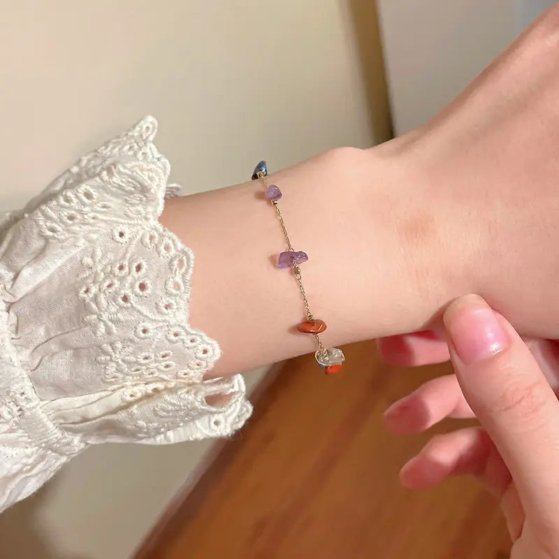 A delicate multicolor gemstone choker in gold and silver alloy featuring a gold-toned chain with colorful irregularly shaped gemstone charms in purple orange and clear.