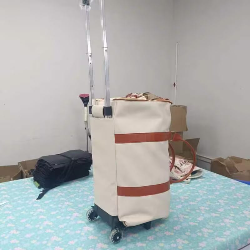 Cream-colored canvas rolling travel bag with large capacity, two horizontal brown leather straps, and a silver telescoping handle designed as a foldable fitness duffel.