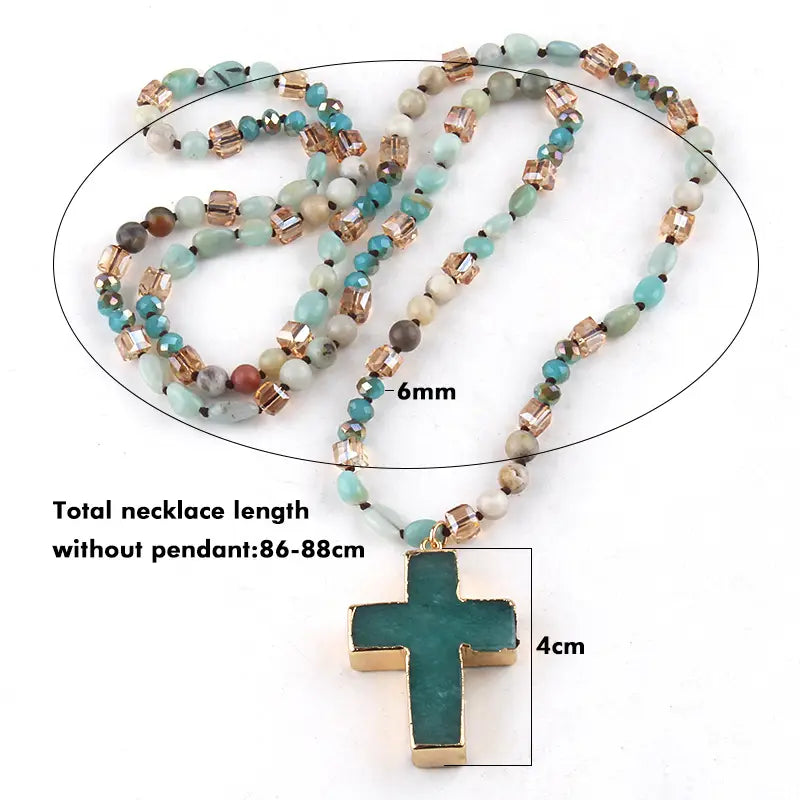 A bohemian natural stone and glass beaded cross pendant necklace featuring a green and gold-toned design with turquoise, rose-gold, and white beads.