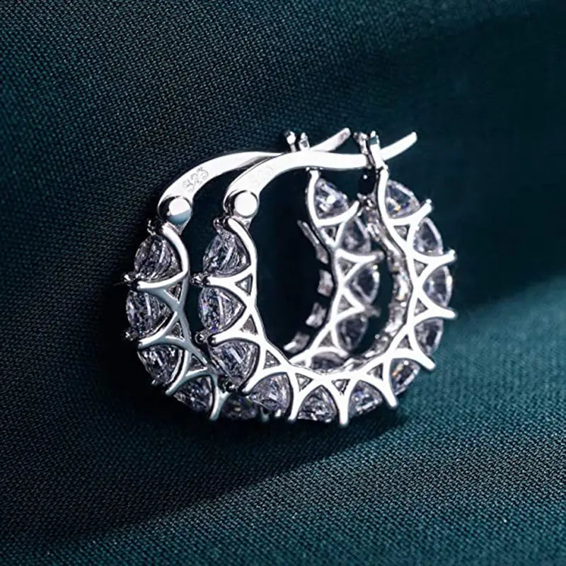 Silver geometric U-shaped hoop earrings with a lattice design and embedded clear zircon crystals.