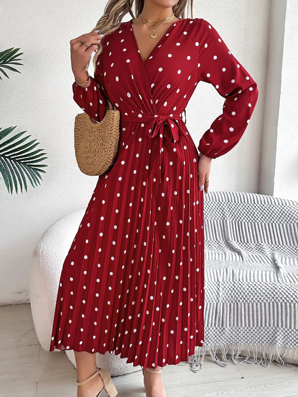 A red polka dot midi dress with long sleeves and a pleated skirt featuring a v neck design.