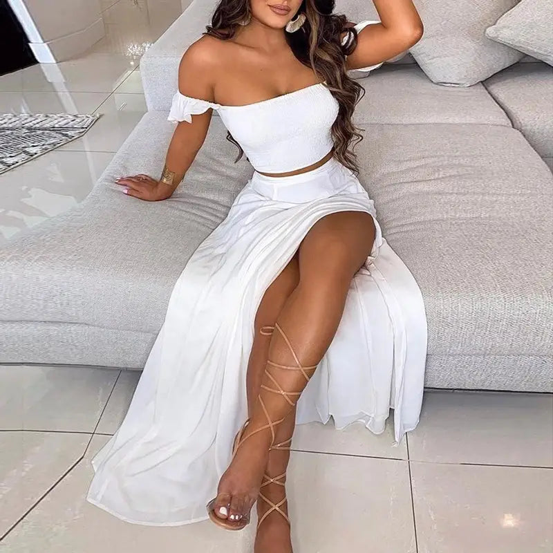 white off-the-shoulder two-piece bohemian maxi dress with ruffled top and high slit skirt in lightweight fabric for casual or beachwear.