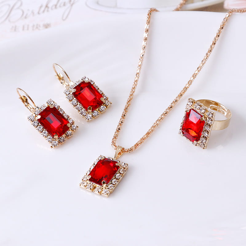 Elegant rectangular gemstone gold jewelry three piece set featuring vibrant red rectangular gemstones surrounded by sparkling clear crystals in a gold-toned setting.