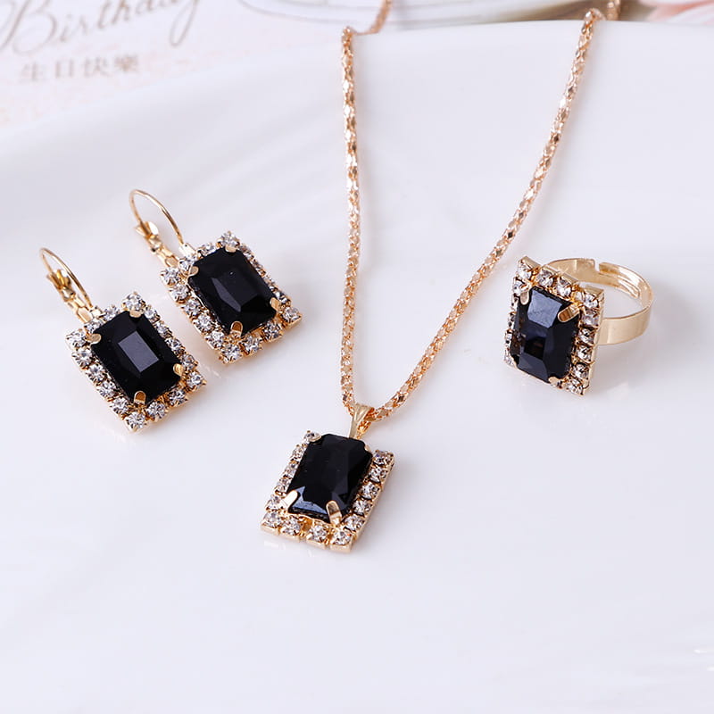 Elegant rectangular gemstone gold jewelry three piece set featuring gold-toned metal with rectangular black gemstones surrounded by sparkling clear crystals.