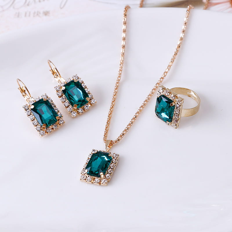 Elegant rectangular gemstone gold jewelry three piece set featuring emerald green rectangular gemstones with gold-tone metal and clear crystal accents.