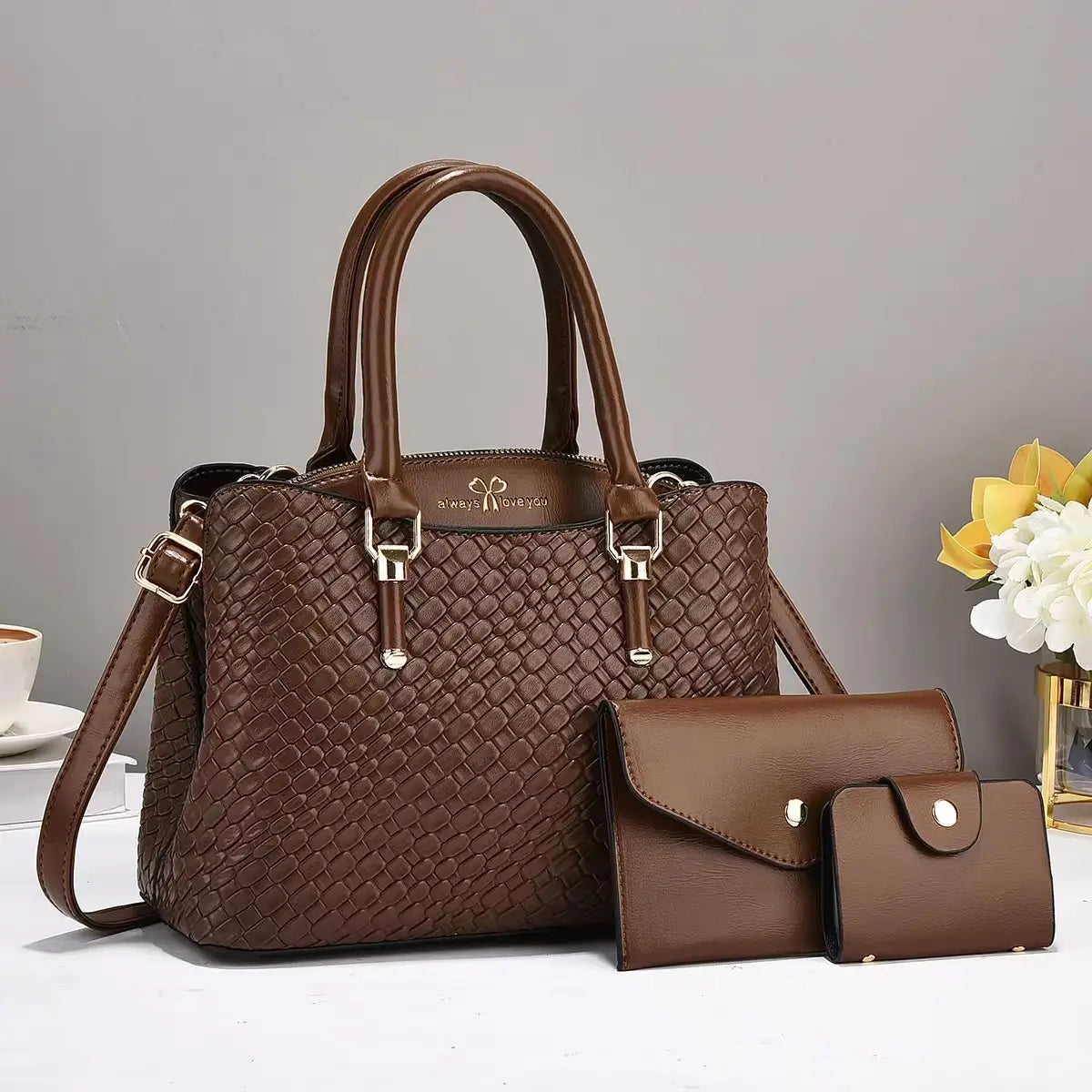 Brown woven leather handbag with gold-tone hardware accompanied by two smaller matching brown wallets in a woven leather three piece handbag set with gold hardware.