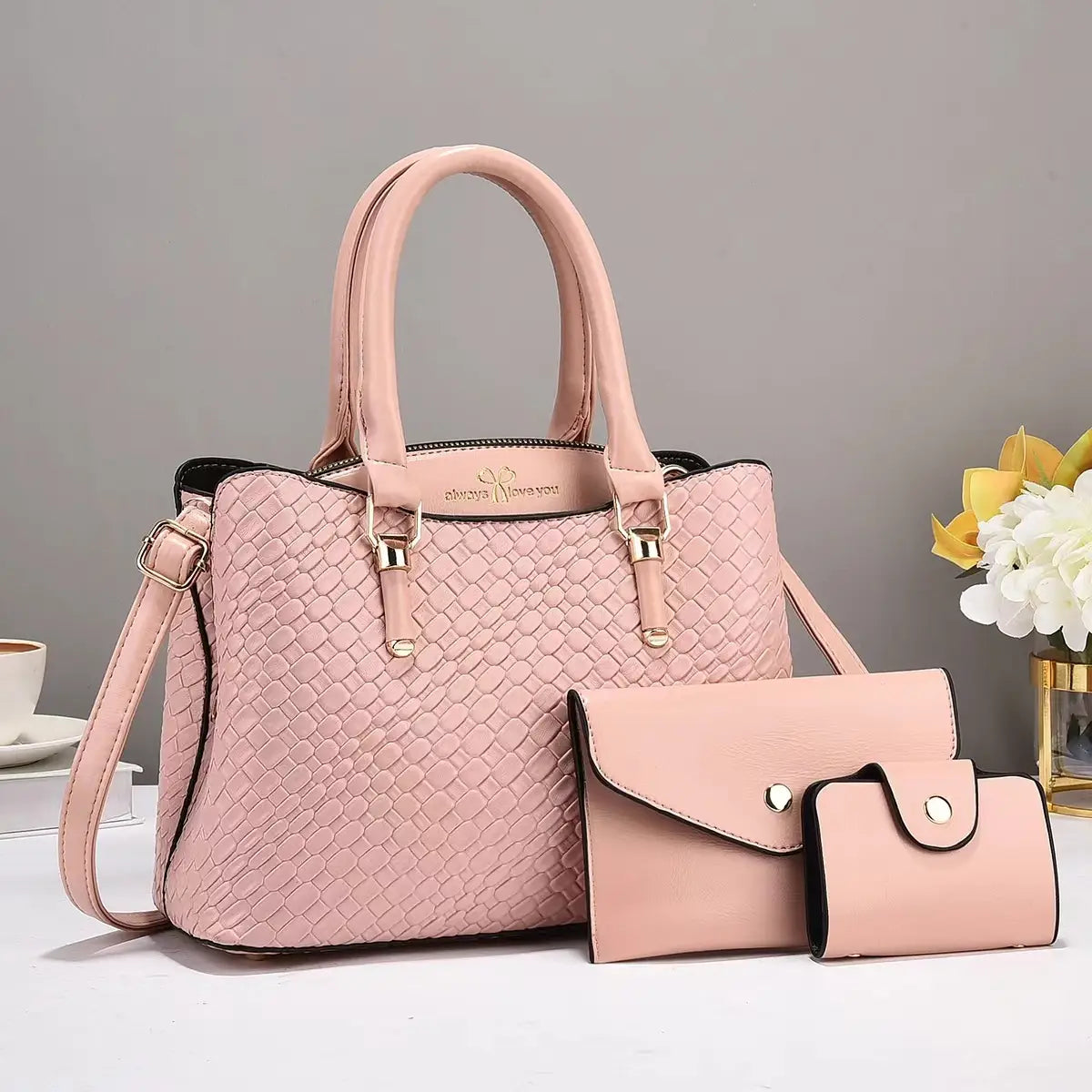 Pink woven leather three piece handbag set with matching clutch and wallet featuring gold hardware.