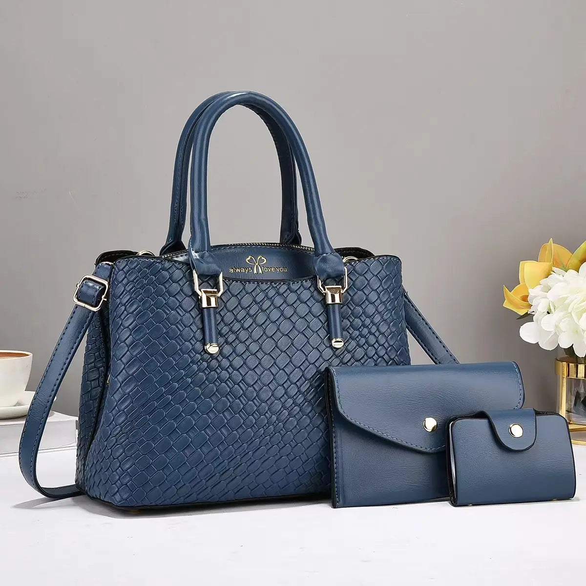 Deep navy blue woven leather handbag with textured pattern and gold hardware accents from a three piece handbag set.