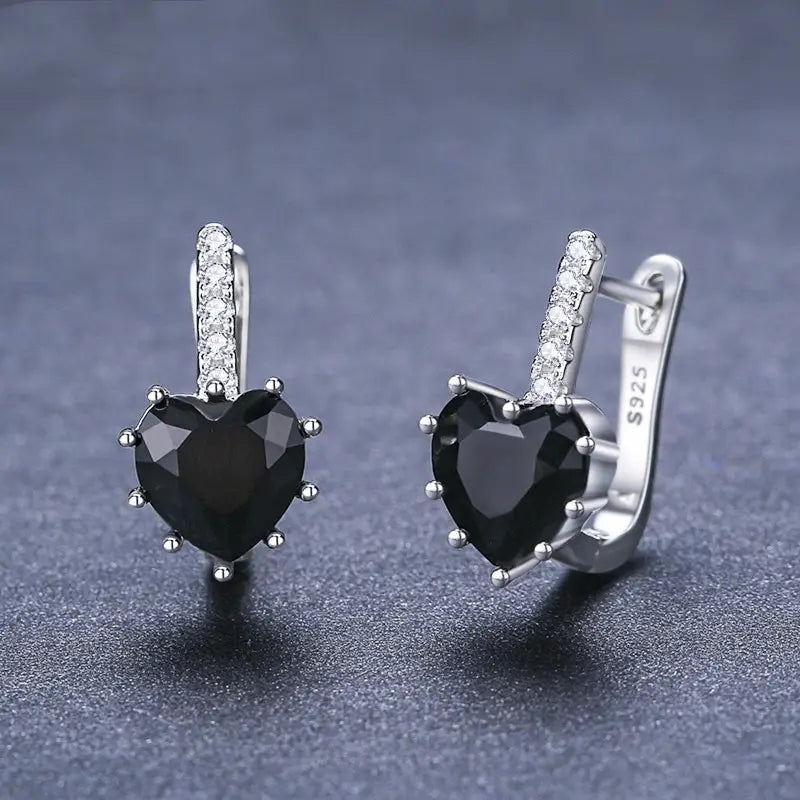 Boucles d’oreilles type huggie en argent avec motif cœur, en argent, présentant une pierre centrale en zircon noir entourée de cristaux transparents et rehaussée de diamants pavés le long de la tige en argent sterling.