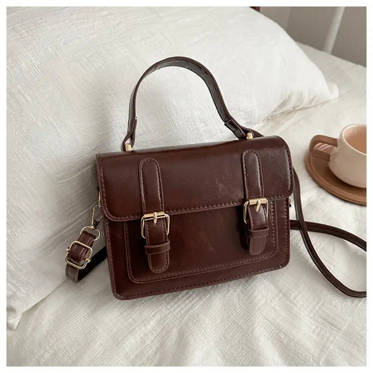 Sacoche en cuir brun avec des boucles en ton or et une anse supérieure, dans une sacoche vintage en effet cuir synthétique à boucles dorées produit.