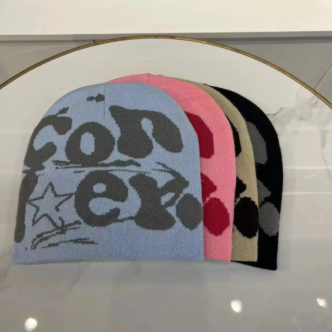 A light blue knitted letter jacquard beanie made of warm knit material featuring a bold gray conex graphic with star and line details designed for winter use.