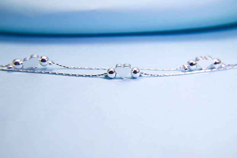 A delicate korean double layer silver heart bead bracelet featuring a central silver heart charm flanked by small spherical beads on either side.