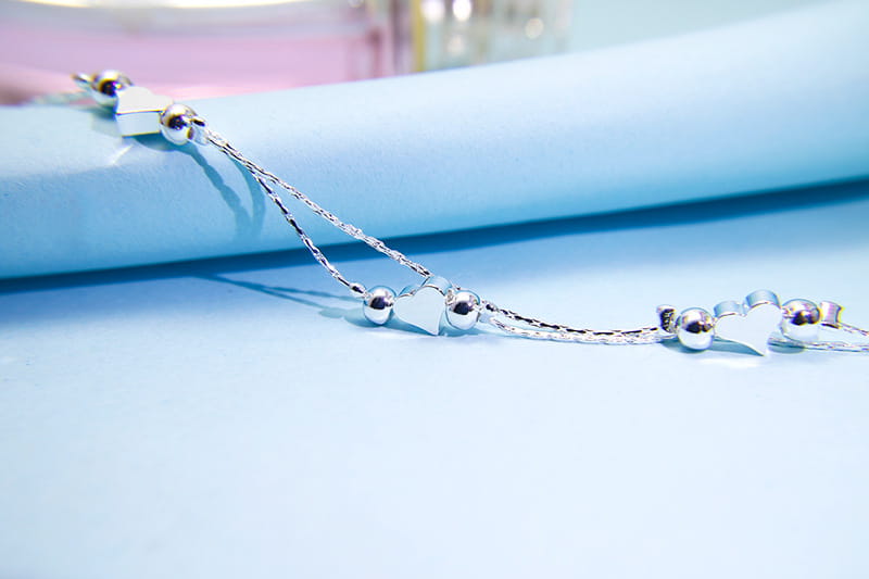 Silver heart-shaped anklet with delicate double layer chain and spherical silver beads in a Korean double layer silver heart bead bracelet design.