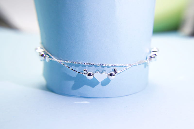 A delicate silver Korean double layer bracelet featuring heart-shaped charms and spherical beads in a double-strand design.