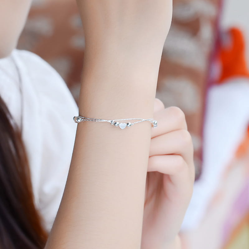 A delicate Korean double layer silver heart bead bracelet featuring a fine chain and small spherical beads.