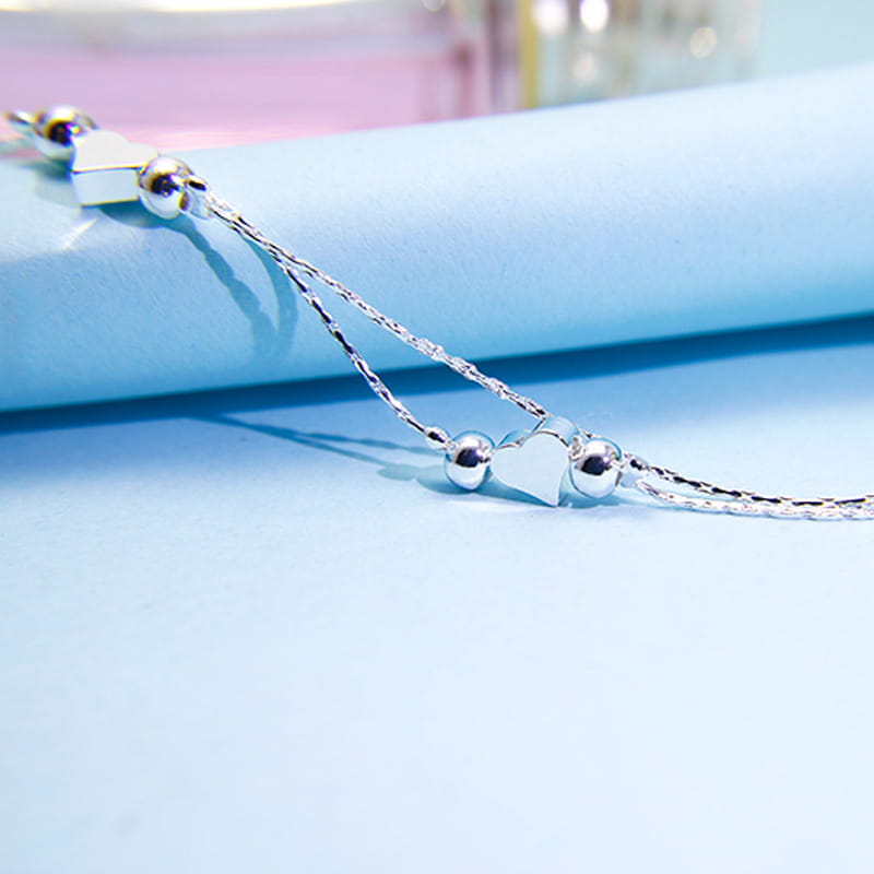 Silver double layer heart-shaped charm bracelet with delicate chain and spherical beads in Korean style.