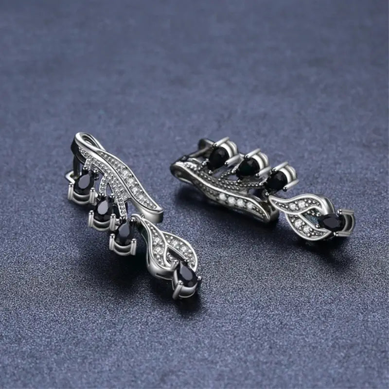 Elegant black teardrop zircon leaf stud earrings featuring silver leaf-shaped clips adorned with black teardrop stones and sparkling clear crystals.