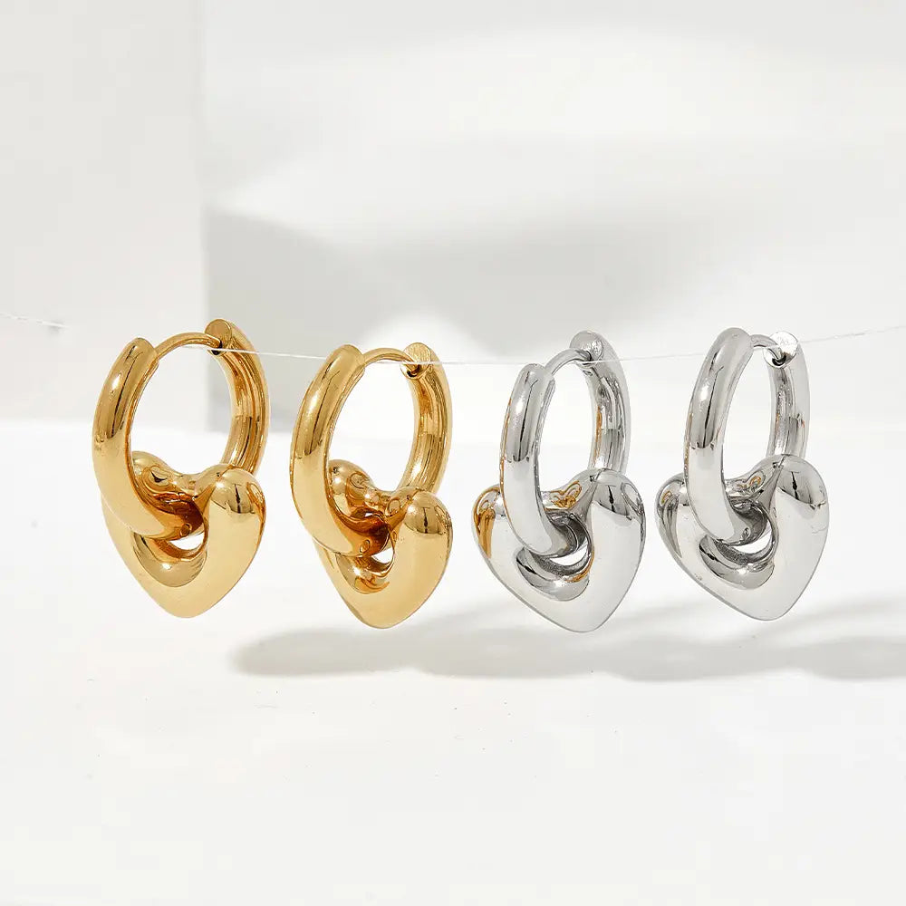 Polished stainless steel geometric charm hoop earrings featuring gold and silver heart-shaped hoops with a polished interlocking knot design.