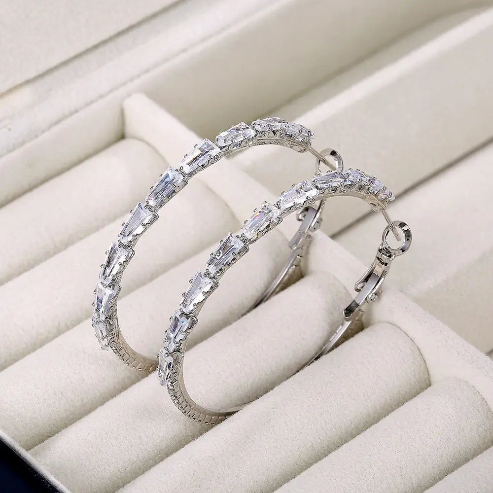 Boucles d’oreilles créoles en argent, ornées d’une rangée de cristaux clairs rectangulaires scintillants en zirconium taillés en baguette.
