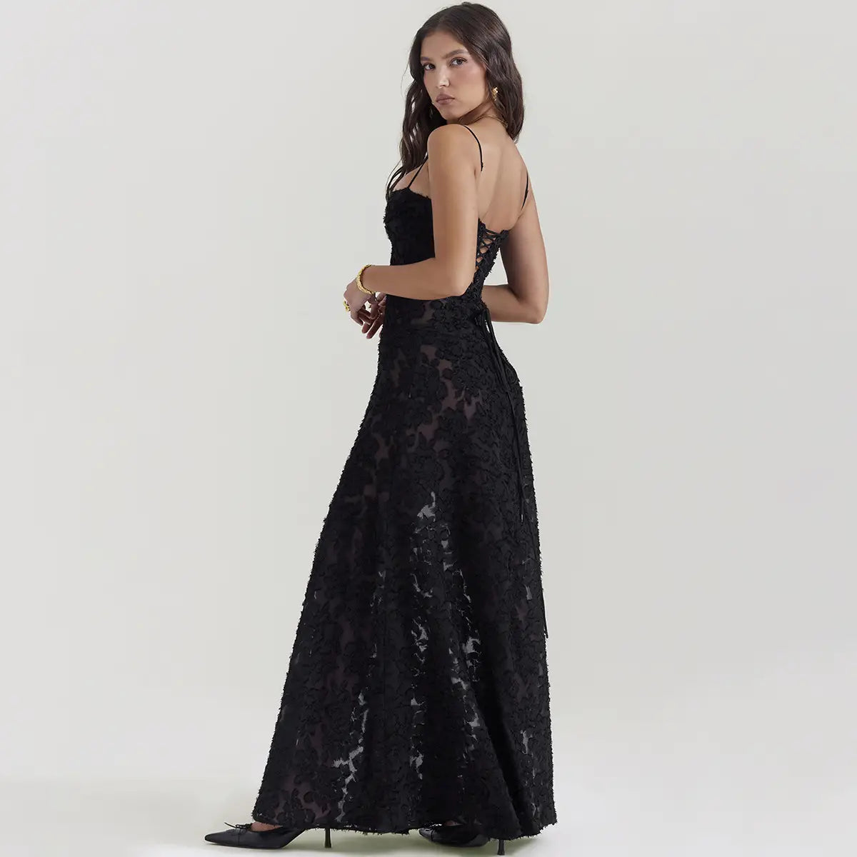 Robe longue maxi élégante à bretelles spaghetti en dentelle noire brodée, présentant des motifs floraux délicats et un corsage ajusté.