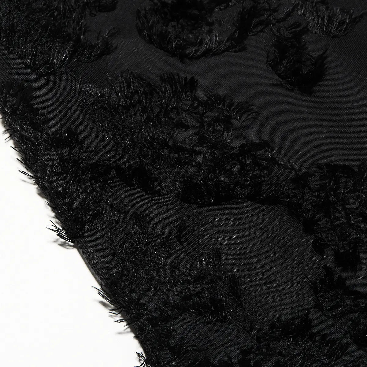 Foulard en tissu noir, orné d’embellissements texturés effilochés, s’accordant avec une robe longue maxi élégante à bretelles spaghetti en dentelle brodée.
