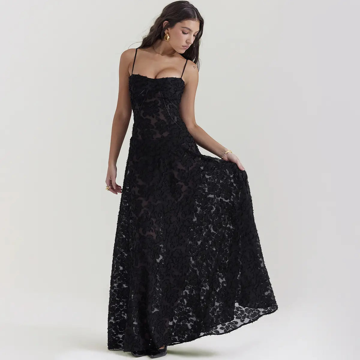 Robe longue maxi élégante en dentelle noire brodée à bretelles spaghetti, présentant des motifs floraux délicats et de fines bretelles.