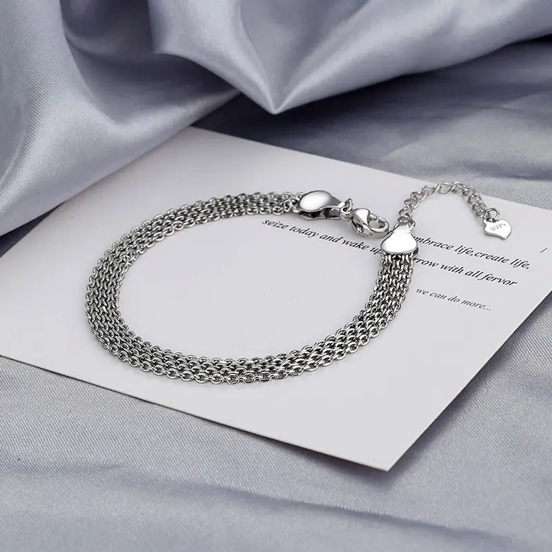 Multi-layer silver mesh heart clasp bracelet featuring a silver-toned multi-strand chain anklet with heart-shaped clasp and a small dangling heart charm.
