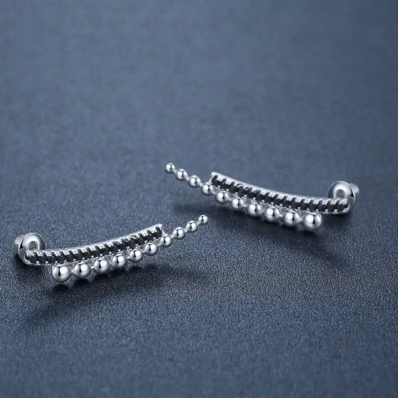 Silver-toned curved ear cuffs with a row of small polished spherical beads featured in black zircon and silver beaded cascading drop earrings.