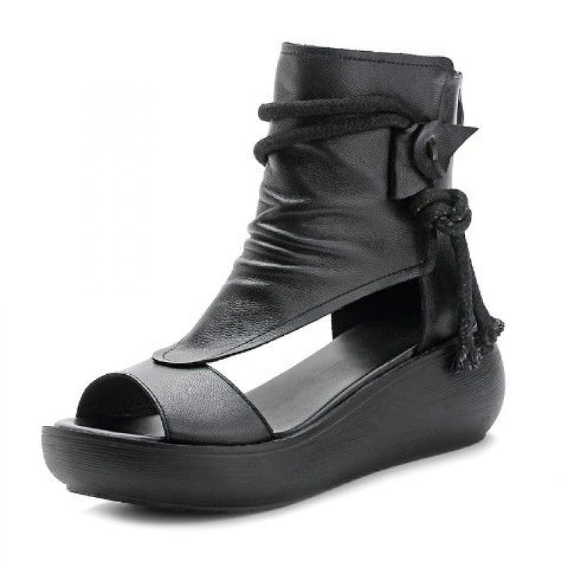 Black leather platform wedge sandals with peep toe design and decorative lace-up ankle strap featuring tassels and buckle detail.
