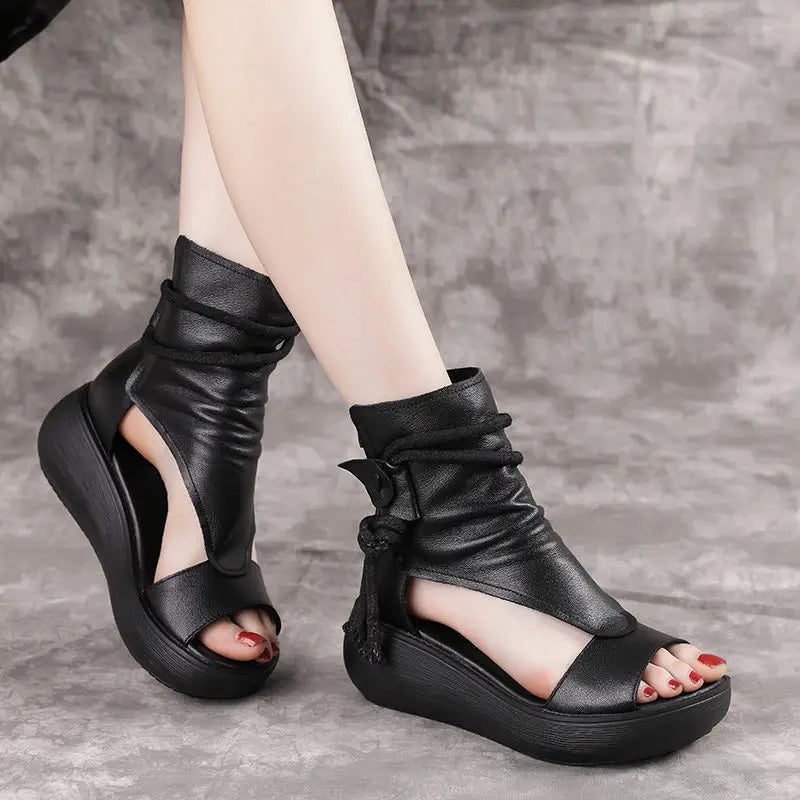 Black leather platform wedge sandals with peep toe, wrapped ankle strap, and tassel detail.