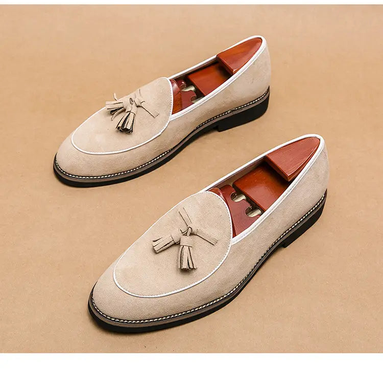 Beige men’s suede tassel loafers made of matte cowhide with white stitching and tassel detail.