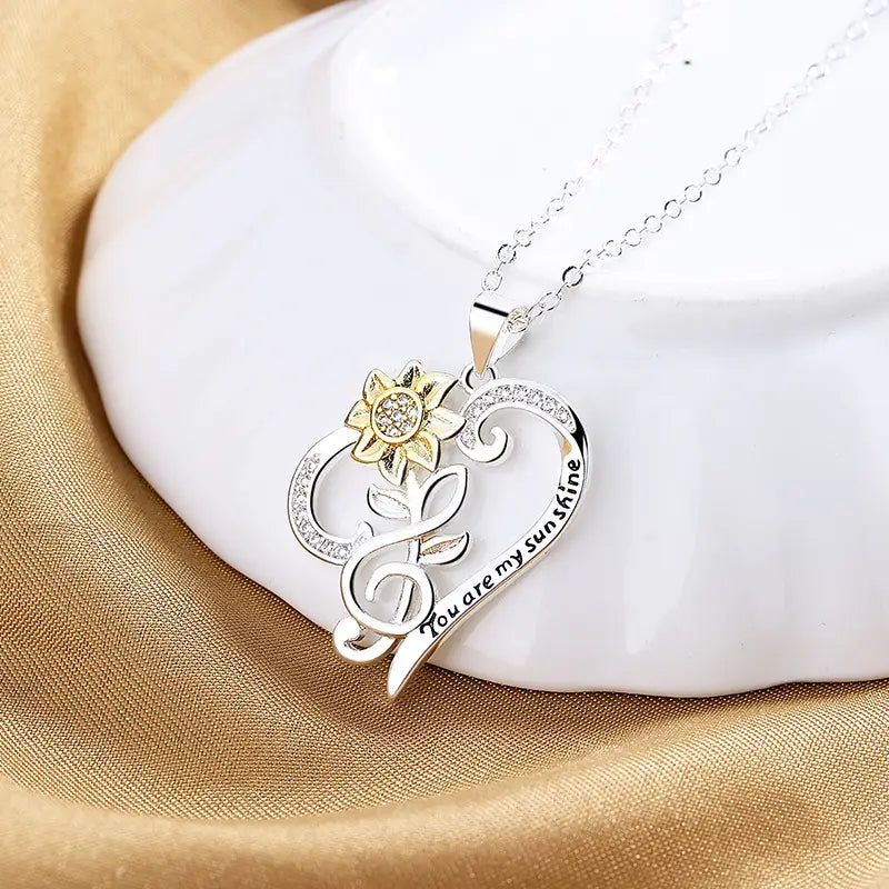 Silver heart-shaped pendant necklace featuring a gold sunflower and an engraved you are my sunshine inscription.