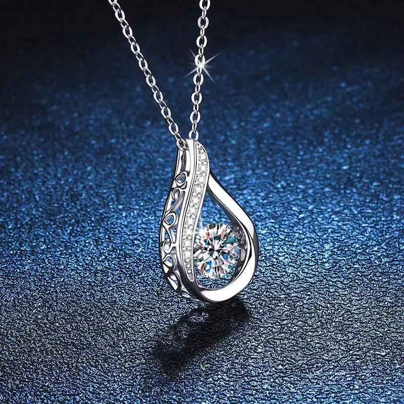 Silver teardrop crystal pave diamond pendant necklace featuring an intricate filigree design with a central sparkling round-cut gemstone and smaller diamonds along its curved edge.