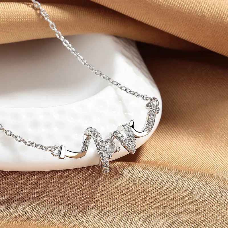 Silver elegant cursive love pendant necklace featuring a delicate chain and an ornate wave-shaped pendant adorned with sparkling clear stones.