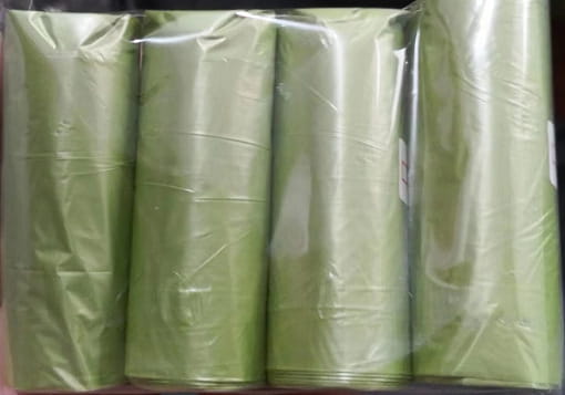 A roll of light green plastic trash bags packaged in clear plastic wrap for use with a cat litter scoop with integrated bag dispenser.