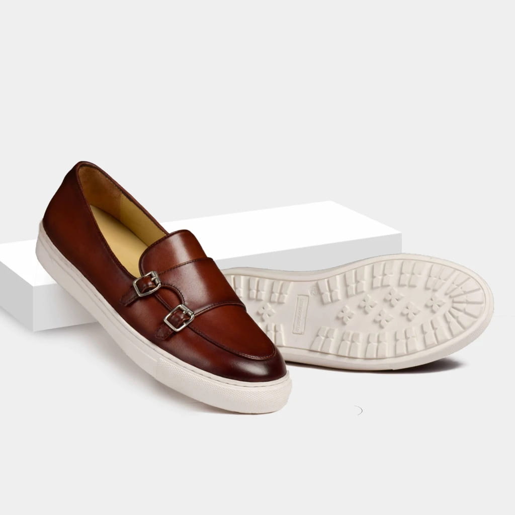 Men’s brown leather double monk strap loafers with silver-toned buckles and a white rubber sole for stylish slip-on wear.