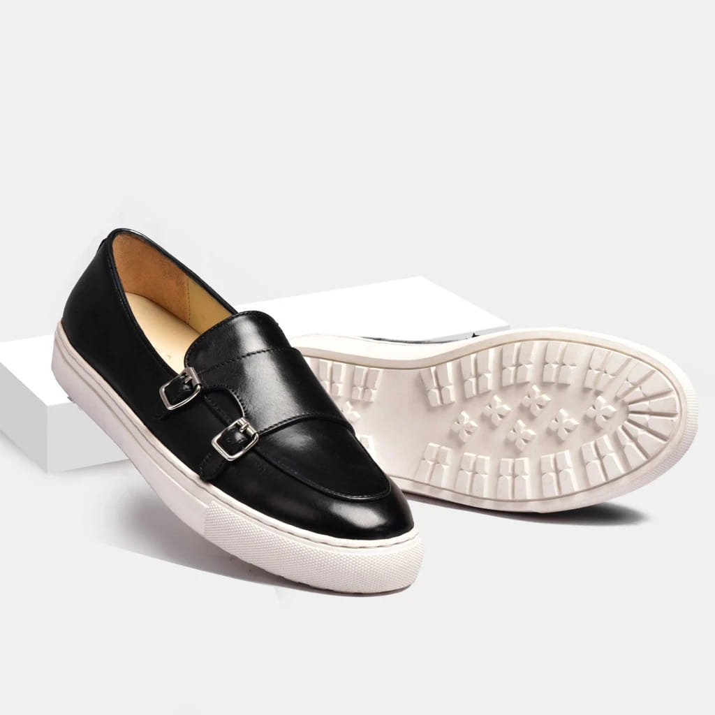 Men’s black leather slip-on loafer with silver buckle detailing and white rubber sole viewed from the back side