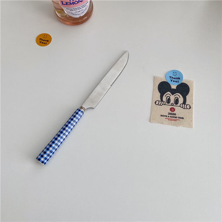 A blue and white checkered handle knife with a stainless steel blade from the checkered stainless steel cutlery tableware set.
