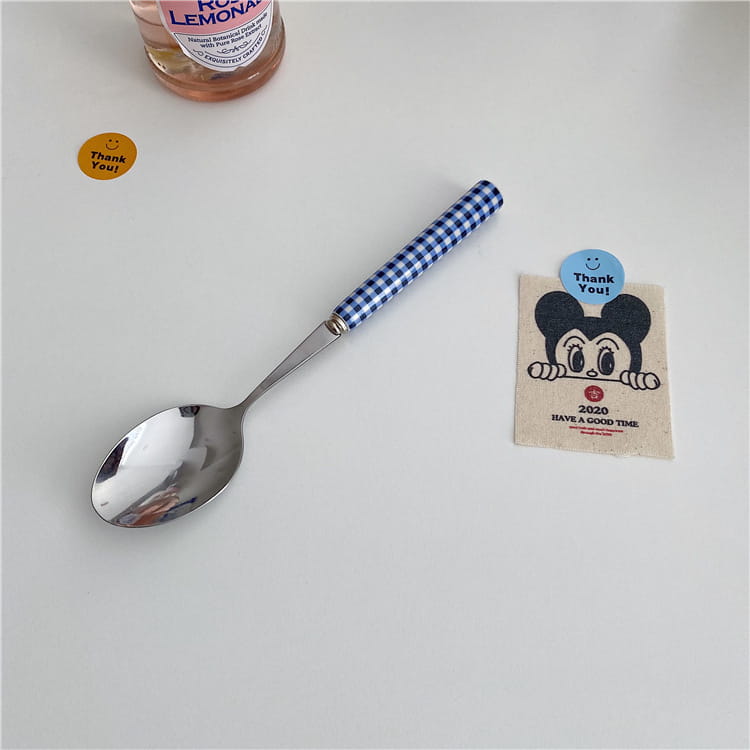 A blue and white gingham patterned stainless steel spoon with a shiny bowl from the checkered stainless steel cutlery tableware set.